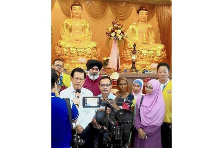 Strengthening ties: A multi-racial delegation on a goodwill visit to temples in Miri led by Lee (in white, speaking to a reporter).