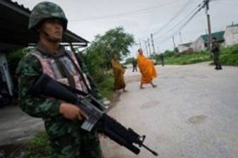 Description: Thai soldiers provide security to Buddhist monks during their daily morning alms collection in the village of Leamnok on the outskirts of Thailand's Pattani. At Wat Lak Muang temple, soldiers armed to the teeth return from patrol in pick-up trucks from time to time, while monks in saffron robes busy themselves.
