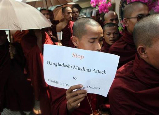 Description: A Buddhist monk holds a banner as they stage a rally outside the Embassy of Bangladesh Friday, Oct. 5, 2012, in Yangon, Myanmar.More than 100 Buddhist monks demonstrated in front of the Bangladesh embassy in capital Yangon on Friday, condemning the recent attacks against Buddhist temples and houses in Bangladesh.(AP Photo/Khin Maung Win)