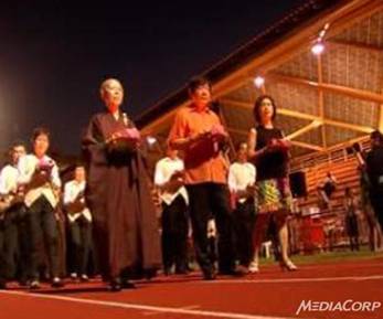Description: Mr Khaw Boon Wan (C) and Buddhist devotees walking around Hougang Stadium with lotus lamps.