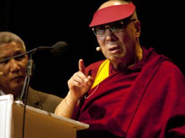 Description: Wearing a visor to shield his eyes from a bright spotlight, Tibetan spiritual leader the Dalai Lama speaks to an audience at the Berkeley Community