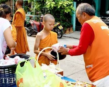 Description: Novice monks in Bangkok receive gifts of food as they participate in alms collecting 