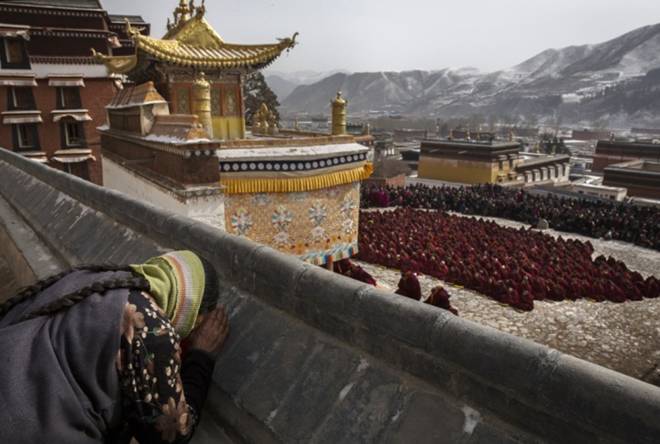 A woman bows her head in prayer as monks take part in special prayers. 