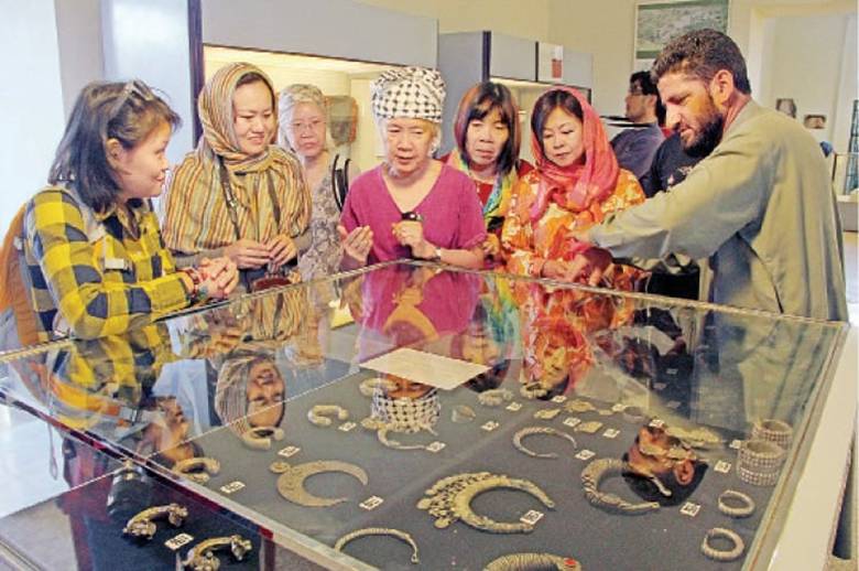 Thai tourists being briefed about Buddhist artefacts at Swat Museum on Wednesday. —  Dawn