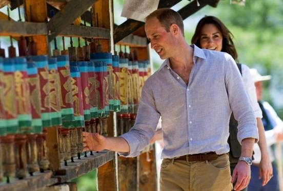 Prince William spins a prayer wheel and Catherine stands behind him.