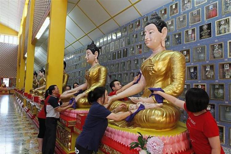 (Left) Volunteers cleaning a Buddha statue at the Wat Chaiya Mangalaram Thai Buddhist Temple in Burmah Lane. (Above) A performance by students of Phor Tay High Schoolduring the Wesak Day celebration organised by the Malaysian Buddhist Association in Burmah Road.