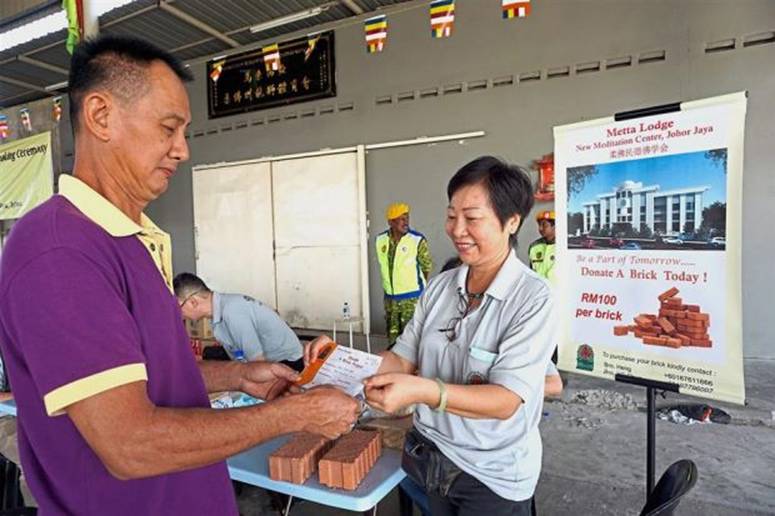 A Metta Lodge member giving a donor a receipt for his donation to the Donate A Brick Project at the groundbreaking ceremony at Taman Johor Jaya.