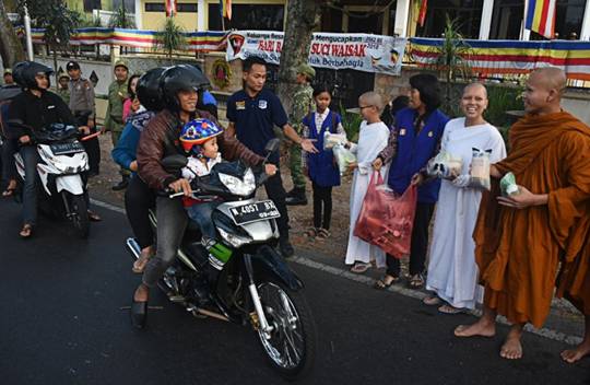 Motorcyclists passing the Dammadipa Arama Vihara on Jl. Raya Ma, Batu, Malang, East Java, get packages of sugary delicacies for breaking the fast, known locally as ‘tajil’, from Buddhist monks during the celebration of Vesak on Tuesday.