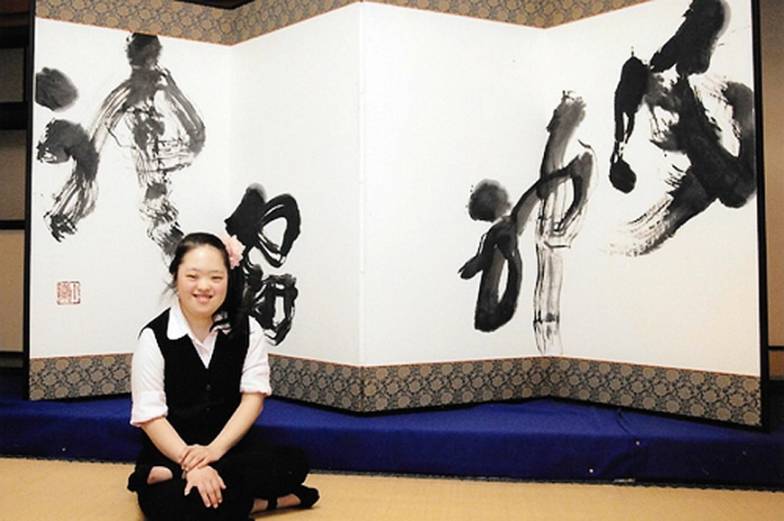 Shōko Kanazawa in front of one of her most famous works, a calligraphic rendition of a 400-year-old painting <i>The Wind And Thunder Gods</i>, which hangs in Kennin-ji in Kyoto. Shoko drew her rendition without ever having seen the original (see below), baffling many art critics. From straitstimes.com