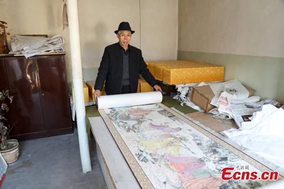 Zhang Zhanping shows his scrolls featuring a Buddhist scripture about 1,250 Arhats, a perfected person who has achieved spiritual enlightenment, in Daixian County, Xinzhou City, North China\'s Shanxi Province, March 18, 2019. The 66-year-old farmer, also a local folk artist specializing in the making and painting of Buddhist sculptures, said he spent eight years creating nine scrolls, each weighing five kilograms and measuring 69 centimetres in width. The total length of the scrolls measured more than 300 meters. He also said he had attempted to apply for a Guinness World Record. (Photo: China News Service/Wang Bintian)